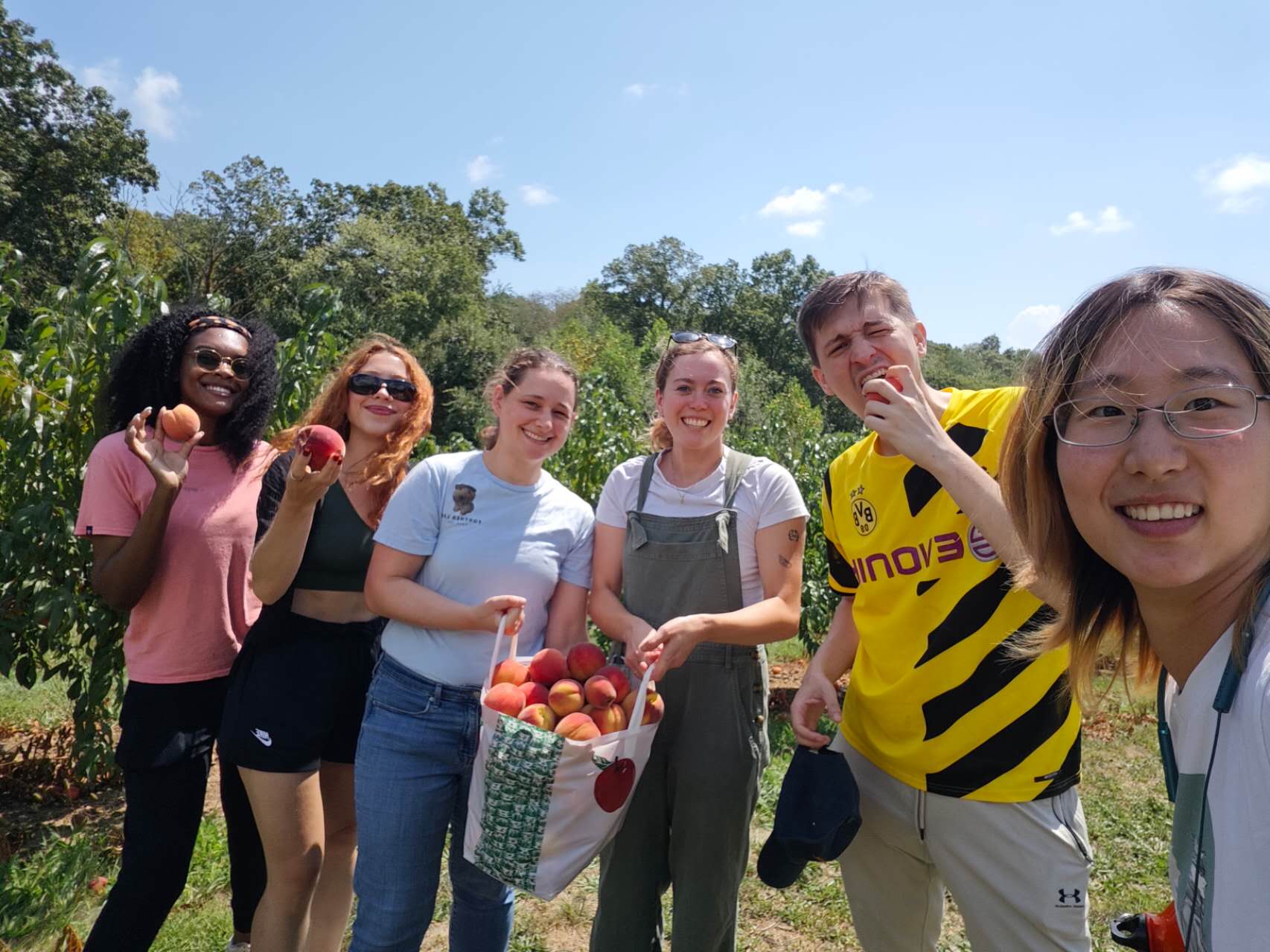 Lab members hold harvested peaches at Bishop's Orchards